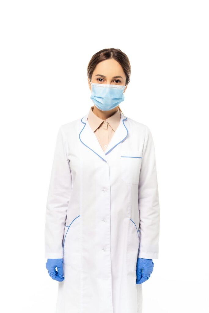 Doctor in medical mask and latex gloves looking at camera isolated on white