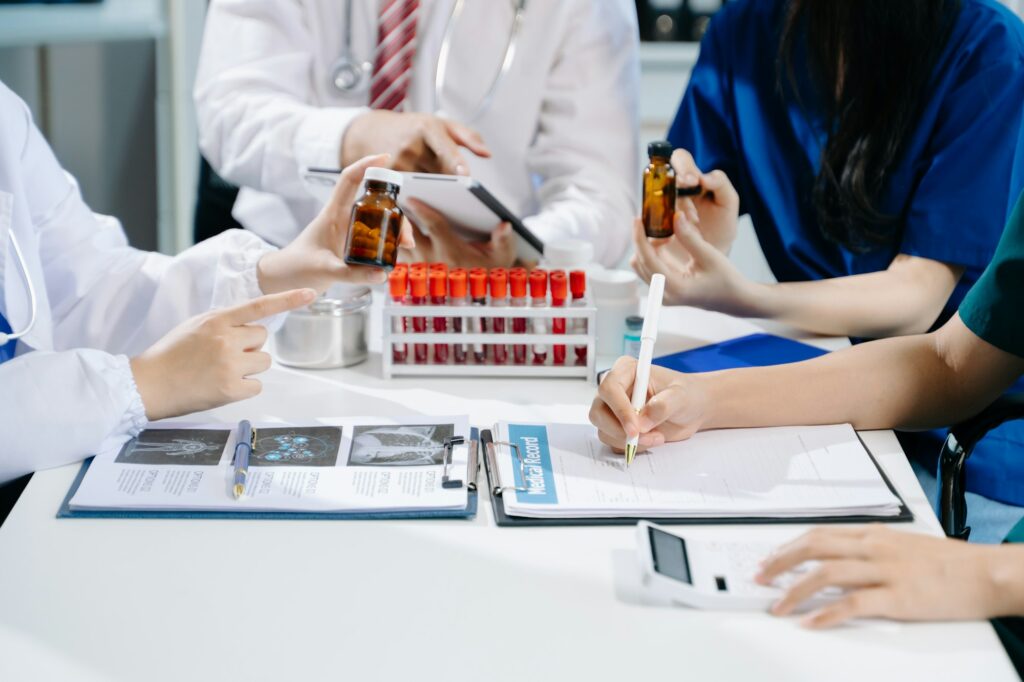 Medical team having a meeting with doctors in white lab coats and surgical scrubs seated